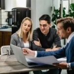 A man and woman sit at a table with a laptop, discussing strategies for building a successful financial advisory practice.