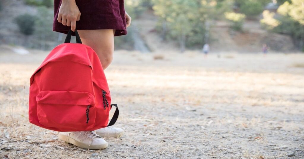 teenager waiting with backpack hand park